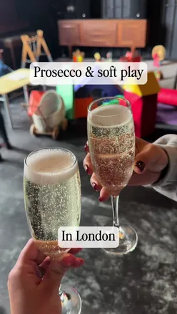 Parents enjoying prosecco at a family-friendly play cafe in London, perfect for toddlers and playtime fun.