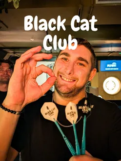 Group enjoying interactive darts and shuffleboard at Black Cat Clubs in Manchester, featuring Halloween cocktails.