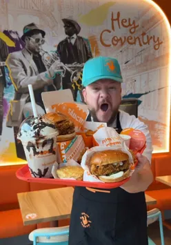 Excited customers at Popeyes opening in Coventry, enjoying free chicken sandwiches and exclusive merch.