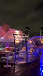 A promotional video showcasing a rooftop bar decorated for Christmas, featuring private dining pods, cocktails, and various food dishes.