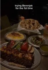 A vlog-style review of Berenjak, featuring a variety of Persian dishes including kebabs, dips, and fresh bread. The creator provides a voiceover commentary on the experience, including the wait time and pricing.