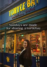 A promotional video for Turtle Bay's Sunday Sharer menu, featuring a creator visiting the restaurant, showing the menu, various Caribbean dishes, cocktails, and the lively atmosphere of the venue.
