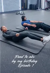 Person doing a core workout with a cousin, aiming for abs by birthday. Gym session with exercise enthusiasm.
