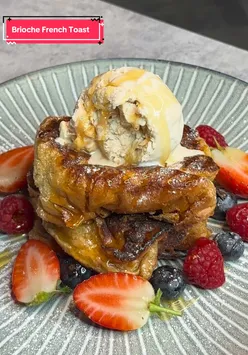 Delicious French toast topped with berries, ice cream, and drizzled with maple syrup, perfect for brunch.