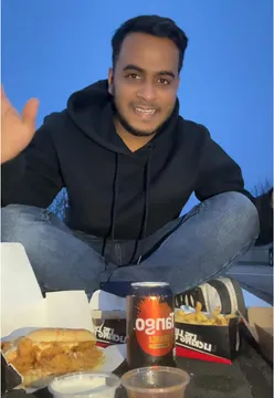 Grateful diner enjoying a burger at dinner time, stylishly dressed in outfit from TrentaZ.