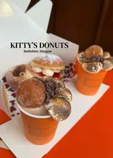 A promotional shot featuring donuts and hot chocolates from Kitty's Donuts in Glasgow, presented in a casual, takeaway-style setting.