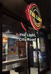 A table laden with a peri chicken burger, onion smash burger, loaded fries, lamb chops, and milkshakes at The Ladz Cardiff.