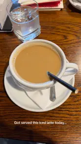 A photo of a hot coffee served in a ceramic cup, captioned as an 'iced latte,' highlighting a discrepancy between the order and the service.