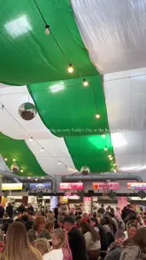 The video is a montage showcasing a St. Patrick's Day celebration at Baltic Market. It features shots of the venue's interior, a live band, a large screen showing sports, and various food and drink items including a layered slushy, lamb shank, pizza, and a dessert bowl. The video uses a handheld style with fast cuts to maintain a lively, festive pace.
