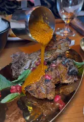 A review of the Permit Room by Dishoom in Liverpool, featuring the creator trying various dishes including lamb chops, samosas, garlic pepper prawns, onion bhajis, chicken ruby, garlic naan, and an ice cream sandwich. The video highlights the venue's all-day bar and cafe concept.