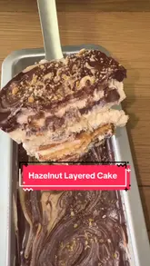 'Indulgent AJ's Hazelnut Layered Cake topped with chocolate drizzle and hazelnuts on a rustic wooden table.'