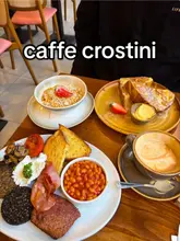 Glasgow cafe Caffe Crostini's bright interior with pastel pink decor, rattan seating, and large windows for natural light.