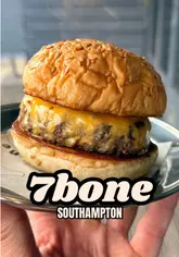 A food review video featuring a creator trying a new burger blend at 7Bone. The video focuses on the quality of the patty and the simplicity of the burger.