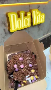 A promotional video showcasing a range of Mini Egg-themed desserts at Dolci Vita, including brownies, cakes, and waffle balls, with a clear view of the menu.