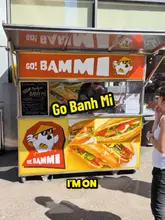 Banh mi sandwich with crispy pork belly, cilantro, and carrots on a cutting board from Go Bammi in Manchester.