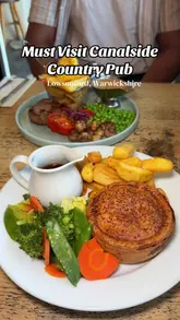 A promotional video for The Fleur de Lys, a canalside country pub in Lowsonford, Warwickshire. The video features a montage of the pub's exterior, interior, and various food items, including their signature pies, steak, chicken dishes, and desserts.