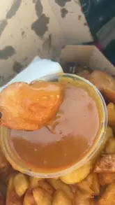 A short, authentic review of a 'spice box' takeaway meal, filmed from inside a car. The creator highlights the variety of items included, such as chips, chicken, and fish bites, and shares their positive opinion on the seasoning and the curry sauce.