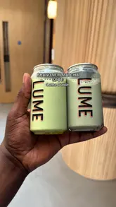 A creator showcases a new brand of canned matcha drinks called 'Lume', demonstrating the product, tasting it, and sharing it with others at an event space.