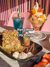 Here are a few options for your alt text, keeping it descriptive and SEO-friendly:

*   **Option 1 (Descriptive):** A slice of layered Dubai Matilda cake and a gourmet ice cream sundae from Sweetbox dessert shop in Cardiff.
*   **Option 2 (Action-oriented):** Close-up of decadent Dubai Matilda cake and an indulgent ice cream sundae at Sweetbox on City Road, Cardiff.
*   **Option 3 (Concise):** Indulgent Dubai Matilda cake and ice cream sundae served at Sweetbox dessert café in Cardiff.

**SEO Tip:** The best option is **Option 2** because it includes the specific location (City Road, Cardiff) and the most popular menu items, which helps search engines categorize your post for food-related searches in that area.