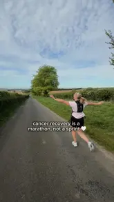 Woman in a bright pink running top smiling at the camera, wearing a medal from a half marathon.