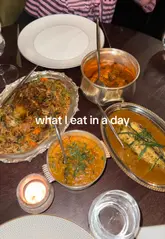 Woman in a bikini with a large Indian meal at Oudh 1722 restaurant in London.