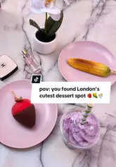 The video features a series of close-up shots of various gelato desserts, including a corn-shaped gelato and a strawberry-shaped gelato, alongside a purple ube matcha drink. The creator is shown holding and eating the desserts in a bright, pink-themed setting.