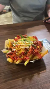 Here are a few options for your SEO alt text, all under 125 characters:

**Option 1 (Descriptive & SEO-focused):**
A variety of loaded fries, a pork gyros, a smash burger, and a chicken burger served at Albert Hall in Swansea.

**Option 2 (Action-oriented):**
Close-up of delicious takeaway meals including loaded fries and burgers at the Albert Hall food hall in Swansea.

**Option 3 (Concise):**
Tasty spread of loaded fries, gyros, and burgers from Albert Hall in Swansea city centre. 

**SEO Tip:** I included "Albert Hall" and "Swansea" in all of these, as those are your primary keywords for local search visibility!
