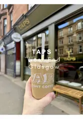 Here are a few options for your SEO alt text, depending on what the photo shows:

**Option 1 (Focus on the brand):**
A customer ordering a drink at the new Taps by Eight Coffee Co shop in the Glasgow West End.

**Option 2 (Focus on the coffee):**
Fresh coffee being poured from a tap at the new Taps by Eight Coffee Co café in Glasgow.

**Option 3 (General/Lifestyle):**
Interior view of the new Taps by Eight Coffee Co coffee shop opening in the Glasgow West End.

**SEO Tip:** I recommend **Option 1 or 2** as they describe the unique selling point (the tap) which helps with search visibility.