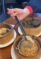 Steaming basket of soup dumplings and siu mai served at a Chinese restaurant in Manchester.