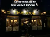 A night-time exterior shot of 'The Crazy Goose' pub and dining room in Brighton. The image captures the storefront with warm lighting, clear signage, and patrons visible through the windows, creating an inviting atmosphere.