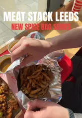 A short, energetic reel showcasing the new 'Spice Bag' menu at Meat Stack in Leeds. The video features quick cuts of the food, including salt and pepper chicken tenders, burgers, curry sauce, and a Lucky Charm milkshake, along with a brief shot of the venue's exterior near the train station.
