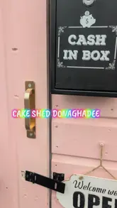 A video tour of The Cake Shed in Donaghadee, an honesty-box bakery. The creator explains how the payment system works and provides a detailed look at the various sweet treats available, including cupcakes, cookies, cake jars, and gluten-free options.