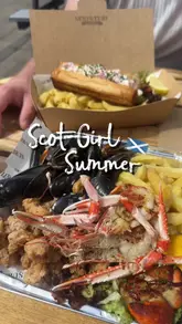 A short, handheld-style video featuring a visit to a seafood venue called Surf & Turf in Dornoch. The creator picks up a takeaway order including a lobster roll and a seafood platter, then enjoys the meal at an outdoor table.