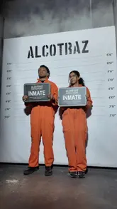 A couple visits Alcotraz, an immersive prison-themed bar. The video follows them through the check-in process, wearing orange jumpsuits, interacting with the actors playing prison guards, and enjoying cocktails in their cell.