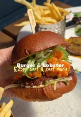 The video presents a sequence of shots featuring the exterior of a Burger & Lobster restaurant, followed by close-ups of various dishes from their surf and turf menu, including beef carpaccio, calamari, a burger, steak, and desserts. The video concludes with a shot of the menu.