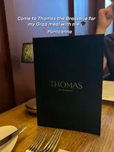 A static, eye-level shot of a restaurant menu placed on a wooden table, intended to promote a graduation meal experience.