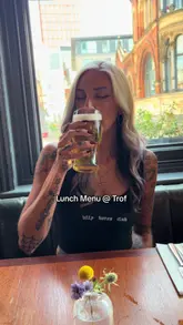 A creator visits The Trof in Manchester to review their new lunch menu, highlighting the Caesar salad, sausage dish, and beef fat chips. The video features shots of the pub's interior, the menu, and the food, accompanied by a voiceover recommendation.