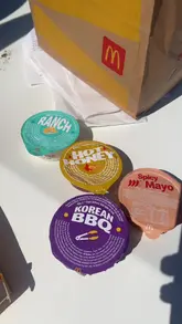 A creator conducts a casual, handheld taste test of new McDonald's sauces in a car park, pairing them with chicken selects and sharing his honest, energetic opinions.