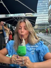 A creator is featured in an outdoor setting, holding a vibrant green cocktail, likely as part of a listicle-style recommendation series for Manchester dining and drinking spots.