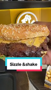 A creator reviews various chicken wings, a smash burger, and a milkshake from Sizzle 'N' Shake, providing visual ratings for each item. The video includes shots of the venue exterior and menu, followed by close-ups of the food being eaten.