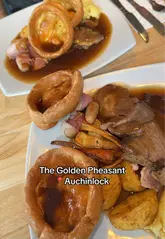 A couple visits The Golden Pheasant in Auchinloch for a Sunday roast, providing a candid review of the starters, main course, and dessert, while also showcasing the venue's atmosphere and outdoor area.