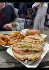 A vlog-style review of a visit to the Merchant City Festival in Glasgow, highlighting the festival atmosphere, street performers, and a specific food stall, Cafe XO, featuring their fried chicken sando, smash burger, and crispy tatties.