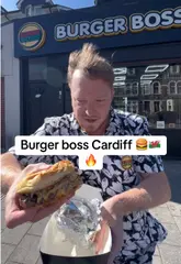 A creator reviews a burger and loaded fries from Burger Boss in Cardiff, providing commentary on the taste and quality of the food while standing outside the venue.