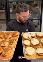 A creator visits 'No Worries Coffee' in Salford, highlighting their massive, freshly baked cinnamon buns (Biscoff, Vanilla, Kinder Bueno) and quality coffee. The video showcases the cafe's interior, friendly atmosphere, and diverse pastry selection, including bagels and cookies.