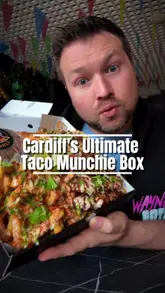 A food review video by a creator visiting Taco Bull in Cardiff to try their 'Munchie Box,' which includes birria tacos, chicken tenders, a double smash burger, and loaded fries.