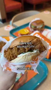 A creator visits the new Popeyes location in Belfast City Centre, providing a behind-the-scenes look at the venue and tasting several menu items including the classic chicken sandwich, tenders, mac and cheese, beans, and a chicken wrap.