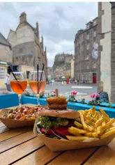 A short, energetic reel showcasing a burger, cocktails, and the outdoor seating area at KickAss Bar in Edinburgh, highlighting the castle view.