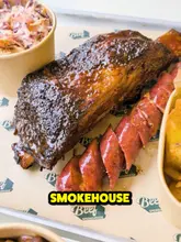 A review-style video featuring a visit to a smokehouse in Manchester. The creator samples various smoked meats, including beef ribs, brisket, sausage, and chicken, alongside sides like mac and cheese and beans, finishing with a banana pudding dessert. The video provides a candid assessment of the food quality and value.