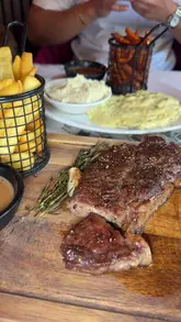 A montage-style promotional video for The Woodlands in Blackburn, featuring shots of the venue's interior, drinks, and various dishes including steak, fried appetizers, and cheesy potato plates.