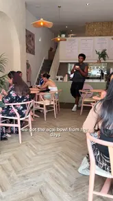A creator visits HER DAYS in Nottingham, providing an honest review of their acai bowl. The video features a tour of the cafe's pink, girly interior and a taste test of the bowl, highlighting the value and quality of the food.